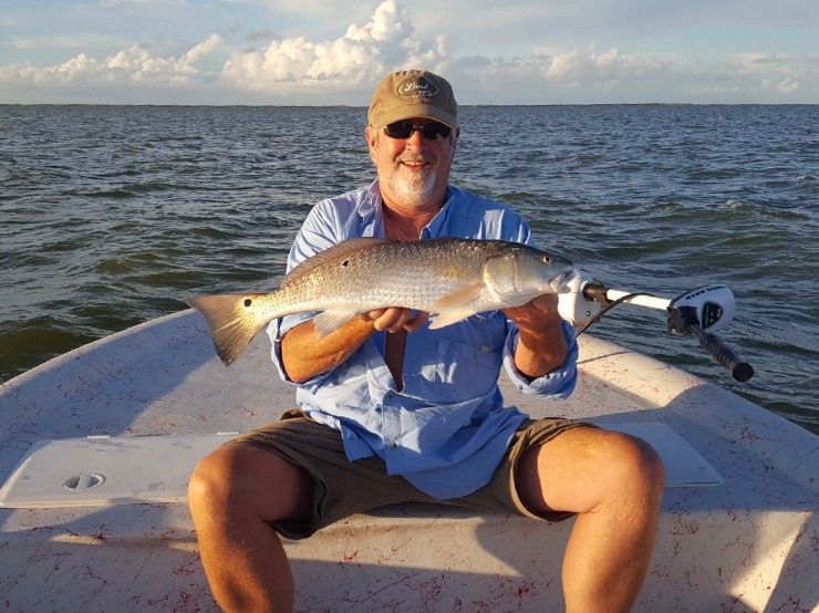 Captain Ryan's dad holding a large redfish and smiling